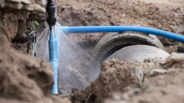 Water pipe break .Exposing a burst water main, focused on the spraying water and the pipe.