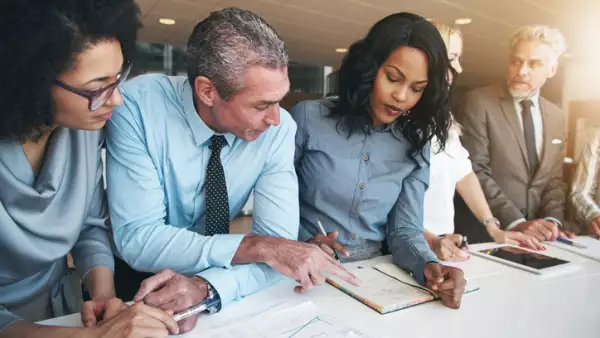Multiracial workers discussing papers sitting in office