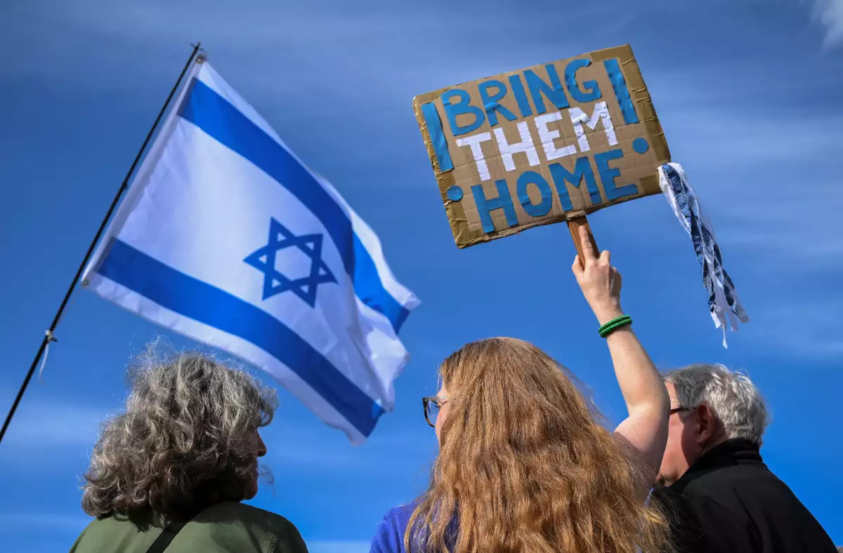 Personas que sostienen una bandera israelí y un cartel que pide traer a los rehenes del ataque del 7 de octubre a casa, se reúnen para un mitin en solidaridad con Israel, después de que Irán lanzara drones y misiles hacia Israel, en Berlín, Alemania, el 14 de abril de 2024.