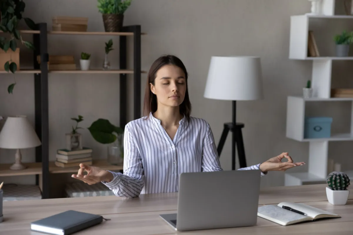 Relaxed peaceful young business woman meditating in office.