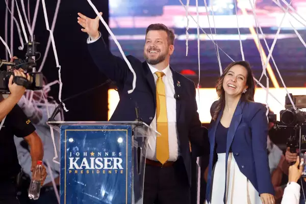 El candidato presidencial chileno Johannes Kaiser (Izqueda) del Partido Nacional Libertario y su esposa Ivette Avaria Vera (R) saludan a los partidarios durante su manifestación de la campaña de clausura en Santiago el 12 de noviembre de 2025