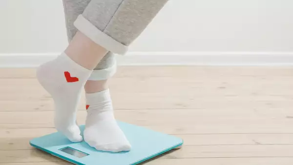 female legs on electronic scales on a wooden floor