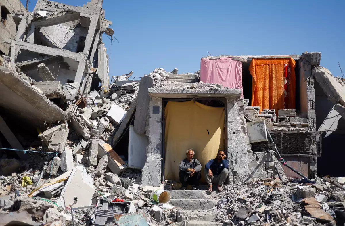 Los palestinos se sientan en su casa que fue destruida en un ataque israelí, en medio del conflicto en curso entre Israel y Hamás, en Khan Younis, en el sur de la Franja de Gaza, el 14 de mayo de 2024.