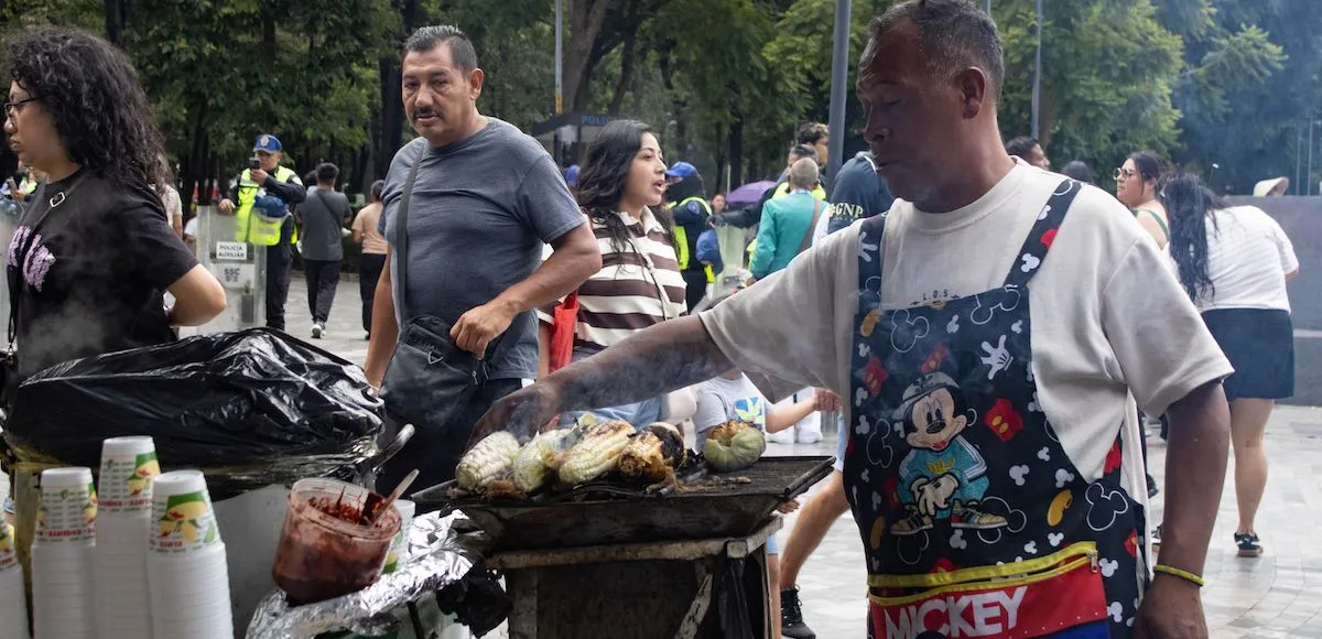 Un hombre vende elotes en la Alameda Central, frente al Palacio de Bellas Artes. 