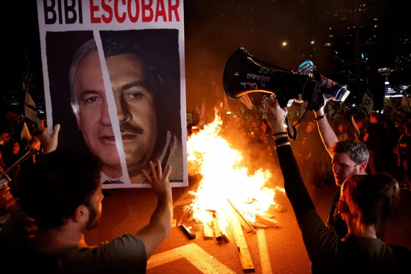 Los manifestantes sostienen sus megáfonos cerca de un incendio en una protesta contra el gobierno del primer ministro israelí Benjamin Netanyahu y por la liberación de rehenes secuestrados en el mortal ataque del 7 de octubre contra Israel por el grupo islamista palestino Hamas desde Gaza, en Tel Aviv, Israel, el 16 de marzo de 2024.