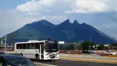 autos y autobus en una vialidad de Monterrey con el cerro de la silla al fondo.