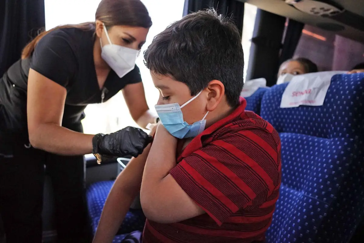 La Secretaría de Salud abre el registro para la vacuna covid para niños. (Niño es vacunado por una enfermera). 