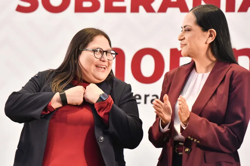 Citlalli Hernández, presidenta de la Comisión Nacional de elecciones de Morena, y Ariadna Montiel, dirigente nacional de Morena, sonriendo. 