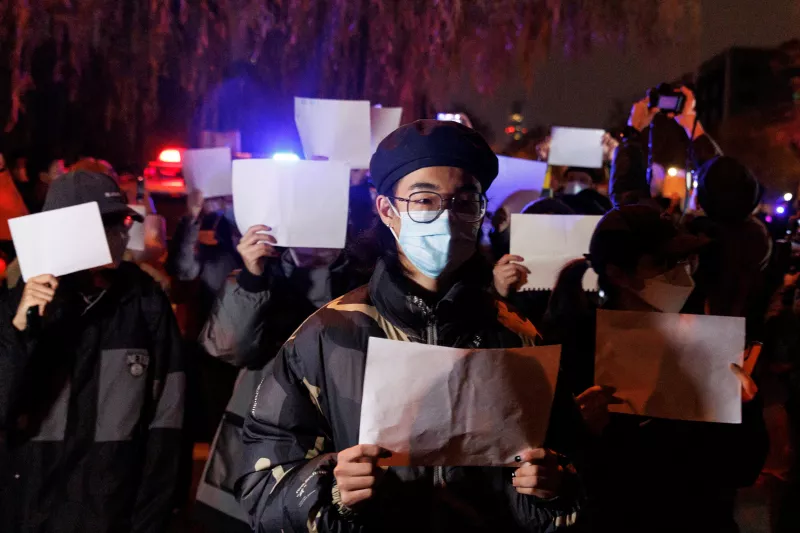 Personas guardan una vigilia con hojas de papel blancas en protestas por las restricciones para contener los contagios de covid-19 en Beijing, China.
