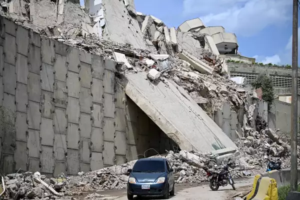 Un automóvil pasa por una estructura colapsada y montones de escombros en Catia La Mar, estado de La Guaira, a unos 30 km al noroeste de Caracas, el 25 de junio de 2026, después de un terremoto.