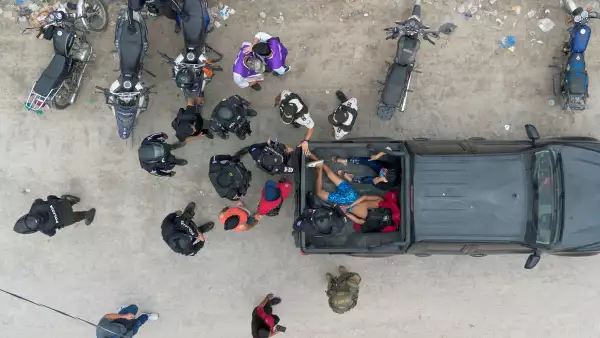 Una vista con un dron muestra a agentes de policía de pie alrededor de un hombre y una mujer que fueron detenidos después de ser encontrados escondidos en una casa abandonada con un chaleco antibalas, durante una operación gubernamental para devolver las casas, supuestamente robadas por bandas de narcotraficantes, a sus legítimos propietarios en Duran, Ecuador, el 19 de julio de 2024.