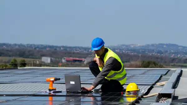 (Trabajador colocando paneles solares en la azotea de un edificio corporativo)