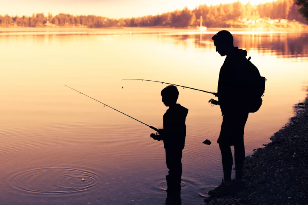Father and son fishing at sunset.