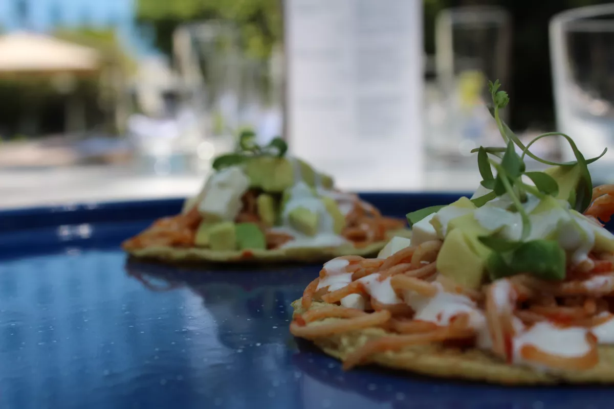 Taco de fideo seco con cubos de queso panela, crema y brotes de cilantro