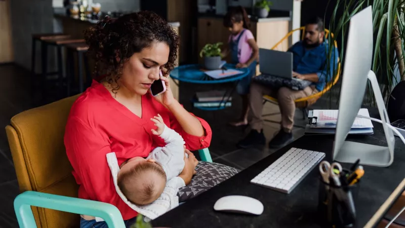 young latin mother working at home using computer while she breastfeeds her baby son in Mexico Latin America, home office concept, hispanic family