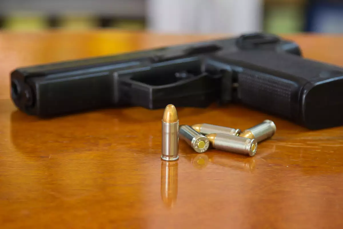 .38 mm handgun and bullets strewn on the rustic wooden table background. Gun with ammunition and isolated ammo or 9mm handgun on wood surface at home. Protect property refers to serious social issues