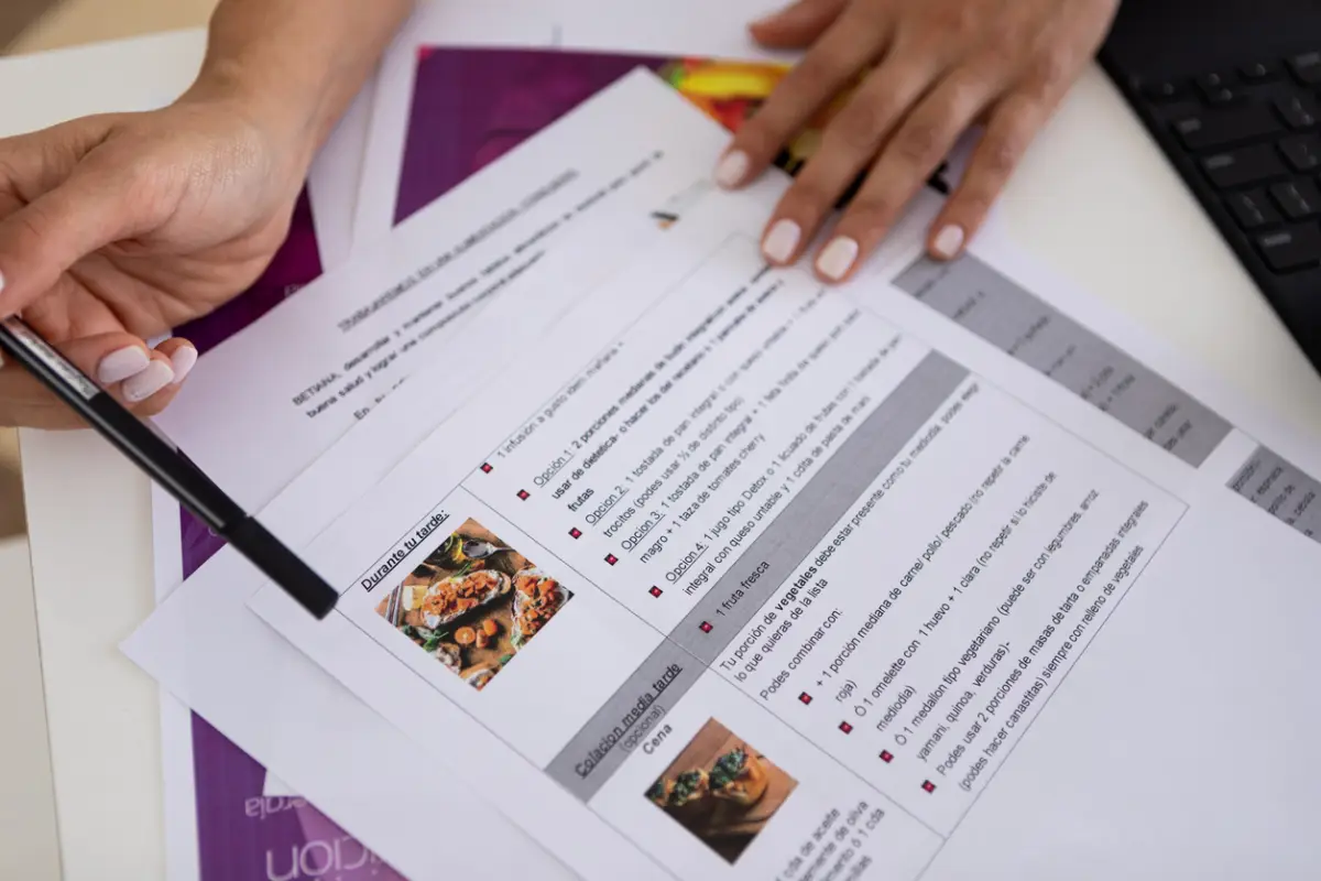Close up of hands of a female nutricionist doctor and deportologist in her desk's office during a medical consultation pointing out a diet plan