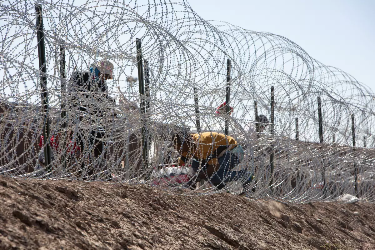 Migrantes se arriesgan a cruzar entre las púas y cuchillas