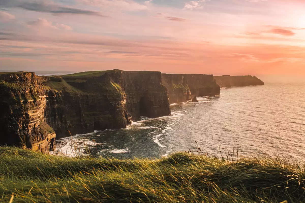 Foto panorámica de un atardecer frente a los famosos acantilados de Moher, en County Clare, Irlanda.