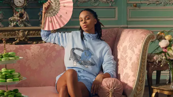 Modelo vestida de azul con una sudadera de la colección de Netflix y Lacoste, con el cocodrilo con una peluca. 