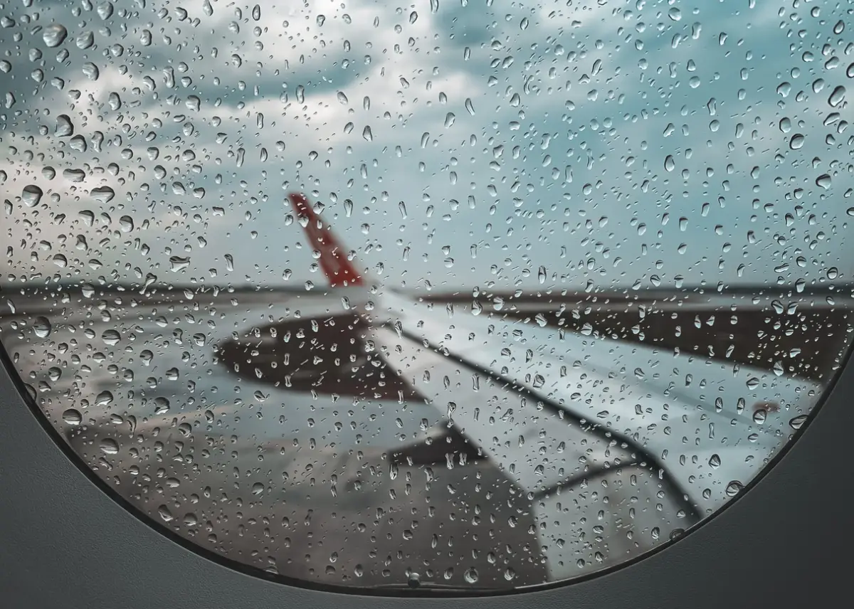 Vista del ala lateral de un avión desde dentro con la ventanilla con poca visibilidad tras el paso de lluvia.