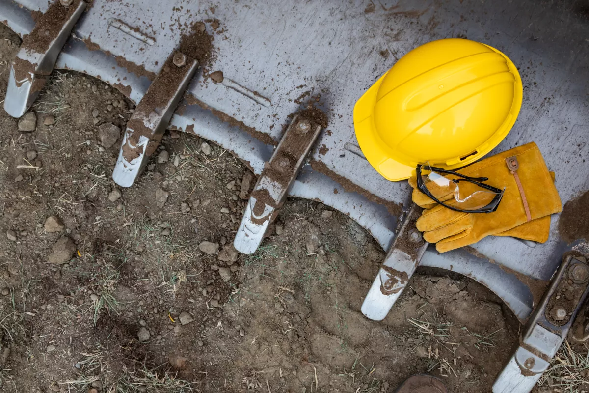 Hardhat, Gloves and Protective Glasses Resting on Bulldozer Bucket Abstract