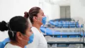 Two nurses wearing protective masks pose inside the new immediate response mobile hospital in Pachuca