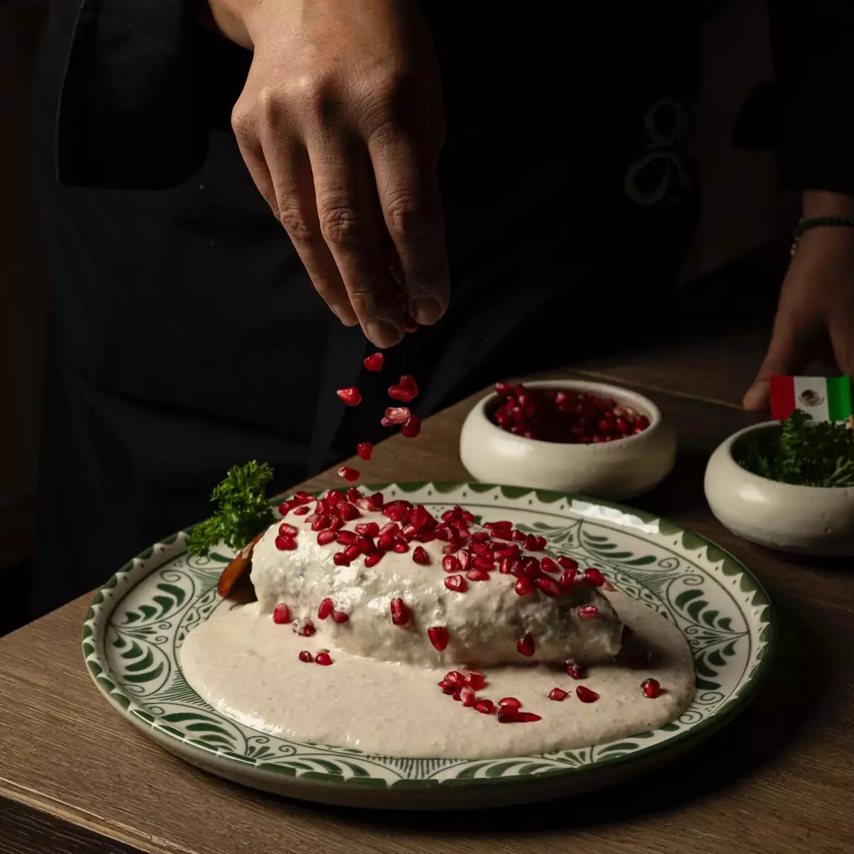 Foto de chile en nogada servido con la salsa (nogada) encima y granos de granada roja.