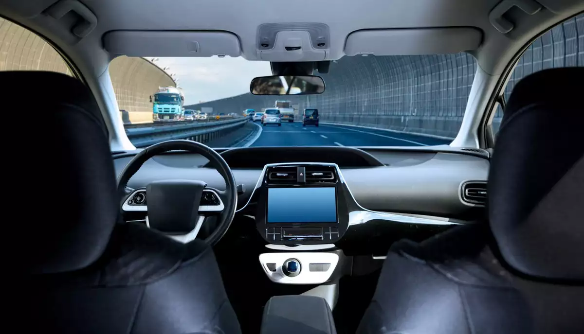 Cockpit of driverless car driving on highway viewed from rear seat.