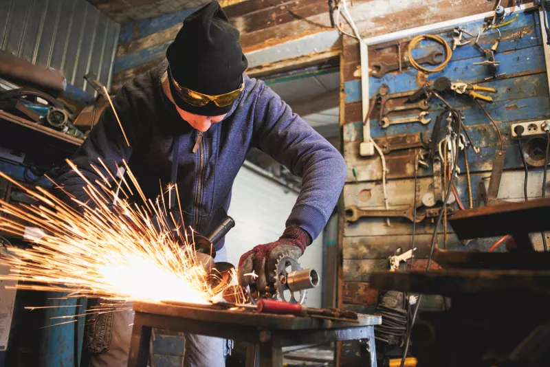 Un hombre trabaja en un taller cortando aluminio. 