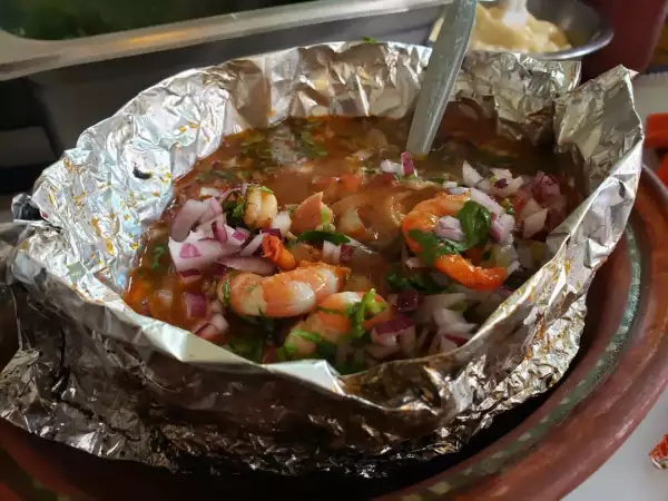 Foto de una sopa de mariscos picosa dentro de un plato hecho de papel aluminio.