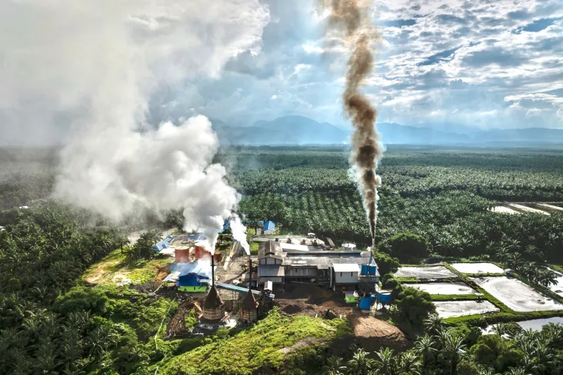 Paisaje con una fábrica que está emitiendo vapor y humo.