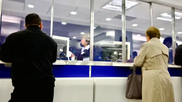 Personas reciben atención en ventanillas de un banco.