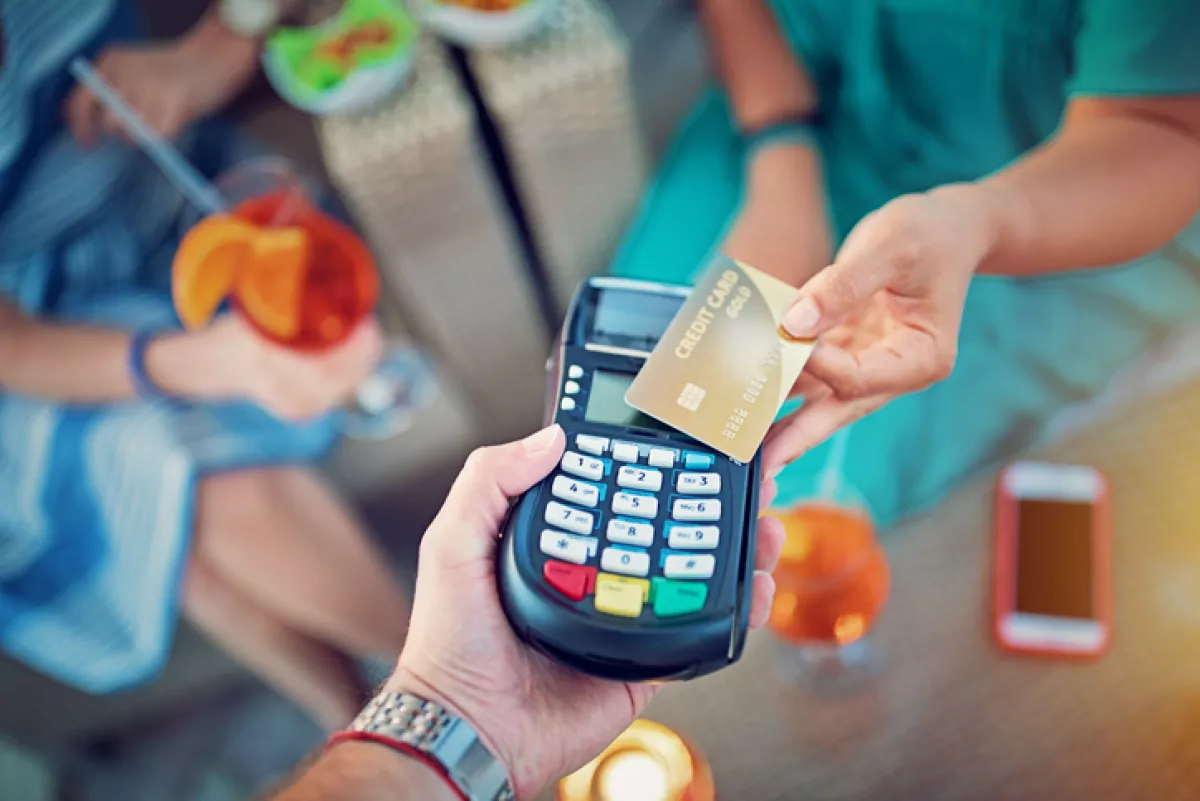 Girlfriends are paying their cocktails on the beach bar using contactless credit card