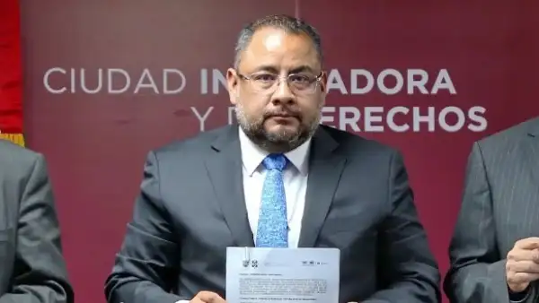 Omar Reyes Colmenares, titular de la Unidad de Inteligencia Financiera, sostiene un documento con ambas manos. 