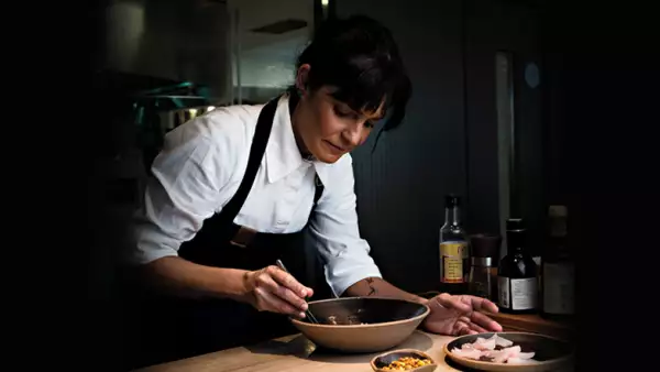 foto de la chef Manu Buffara en la cocina, emplatando uno de sus platillos insignia del restaurante que mantiene en Curitiba