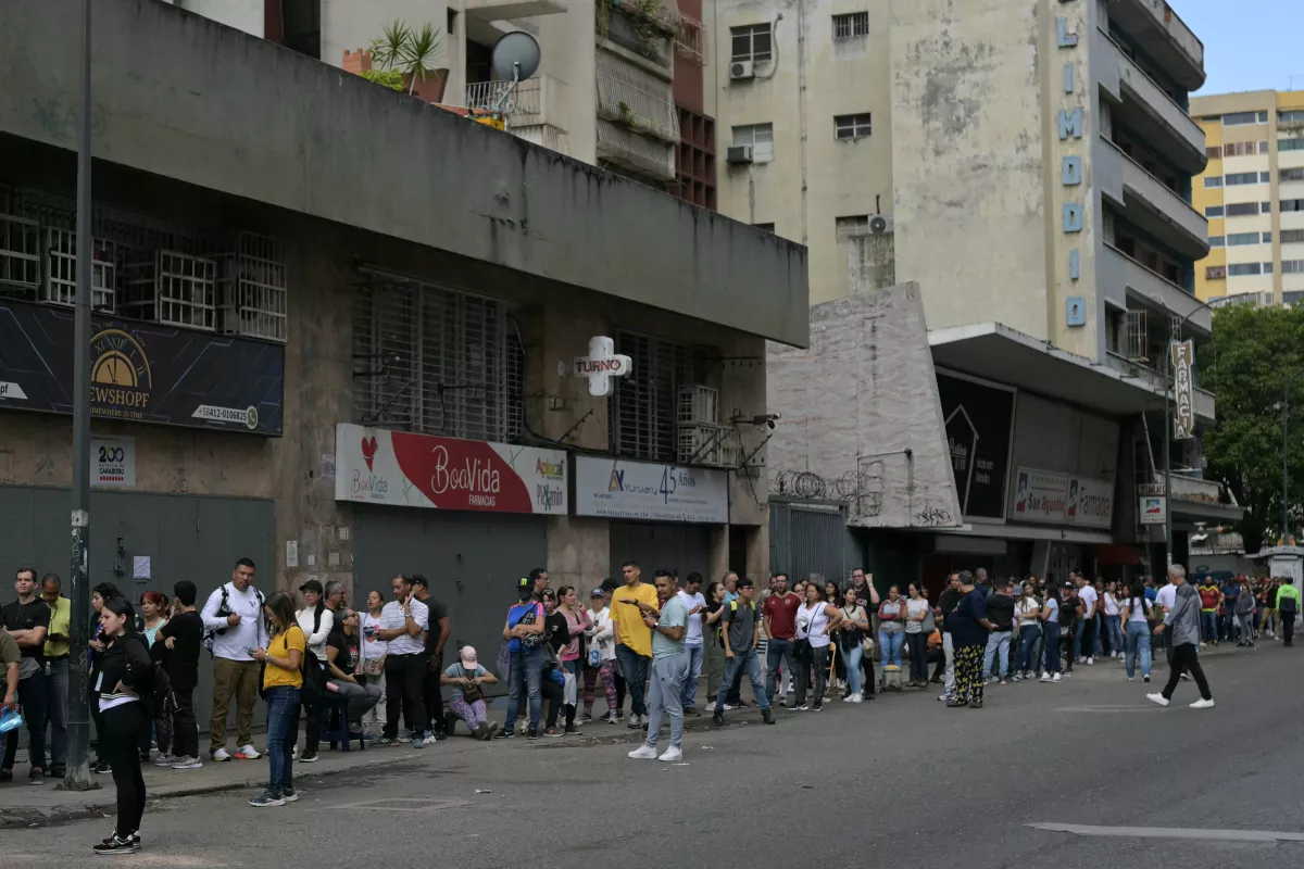 La gente hace cola afuera en un centro de votación en Caracas durante las elecciones presidenciales venezolanas del 28 de julio de 2024. Los venezolanos votan el domingo entre la continuidad del presidente Nicolás Maduro o el cambio en su rival Edmundo González Urrutia en medio de una alta tensión después de la amenaza del titular de un "baño de sangre" si pierde, lo que las encuestas sugieren que es probable.