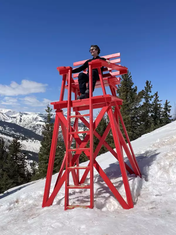 Hombre sentado en una silla roja con la nieve de fondo 
