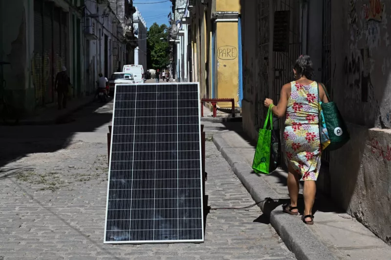 Una mujer pasa junto a un panel solar durante un corte de energía a nivel nacional en La Habana el 6 de julio de 2026.