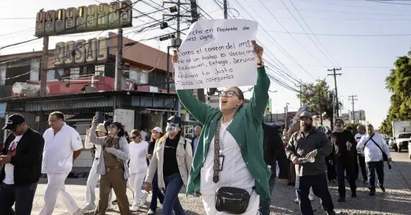 Al menos 12 personas entre hombres y mujeres avanzan sobre una avenida, algunas visten de blanco y verde y portan pancartas.jpg