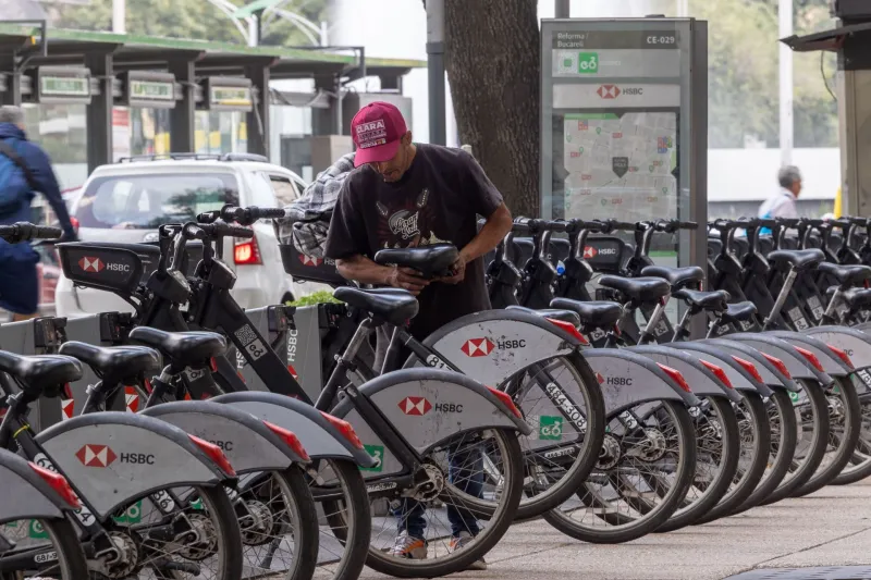 Un usuario del sistema de movilidad personal Ecobici ajusta una bicicleta, en una de sus estaciones, ubicadas en avenida Reforma.