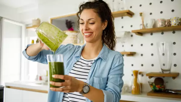 Young woman preparing a green smoothie at home