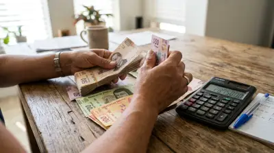 Closeup de las manos de una mujer contando billetes de pesos mexicanos. Las denominaciones son: 50, 100, 200 y 500 pesos.