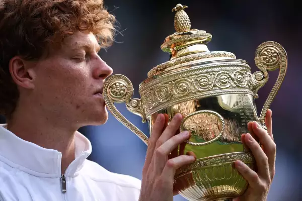 El italiano Jannik Sinner besa el trofeo del ganador mientras posa para fotos después de su victoria contra el español Carlos Alcaraz al final de su partido final de tenis de individuales masculinos en el decimocuarto día del Campeonato de Wimbledon 2025 en The All England Lawn Tennis and Croquet Club en Wimbledon, suroeste de Londres, el 13 de julio de 2025.