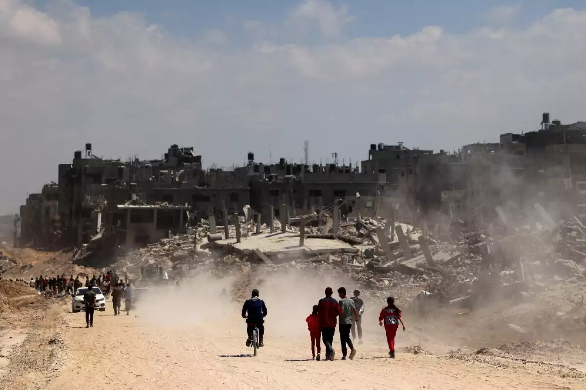 Los palestinos utilizan una carretera bordeada con edificios dañados y destruidos en Khan Yunis el 7 de abril de 2024 después de que Israel retirara las tropas del sur de la Franja de Gaza, seis meses después de la devastadora guerra tras los ataques del 7 de octubre.