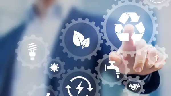 Concepto de desarrollo sostenible en pantalla con íconos de energía renovable, preservación de recursos naturales, protección del medio ambiente dentro de engranajes conectados, persona de negocios en segundo plano