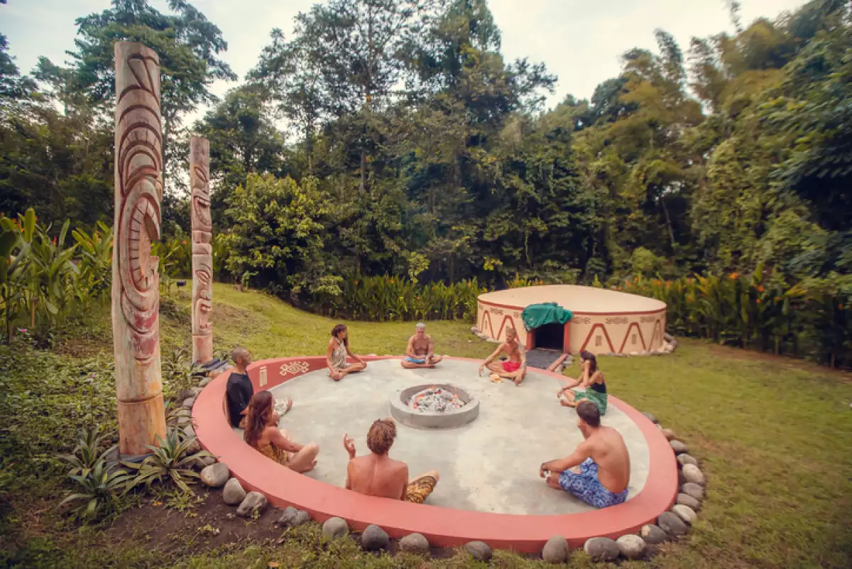 Group of people preparing for Mayan Temazcal- traditional steam sauna bath of Mesoamerican cultures. Diverse multiethnic friends sitting on grass and taking training course before Temazcal experience