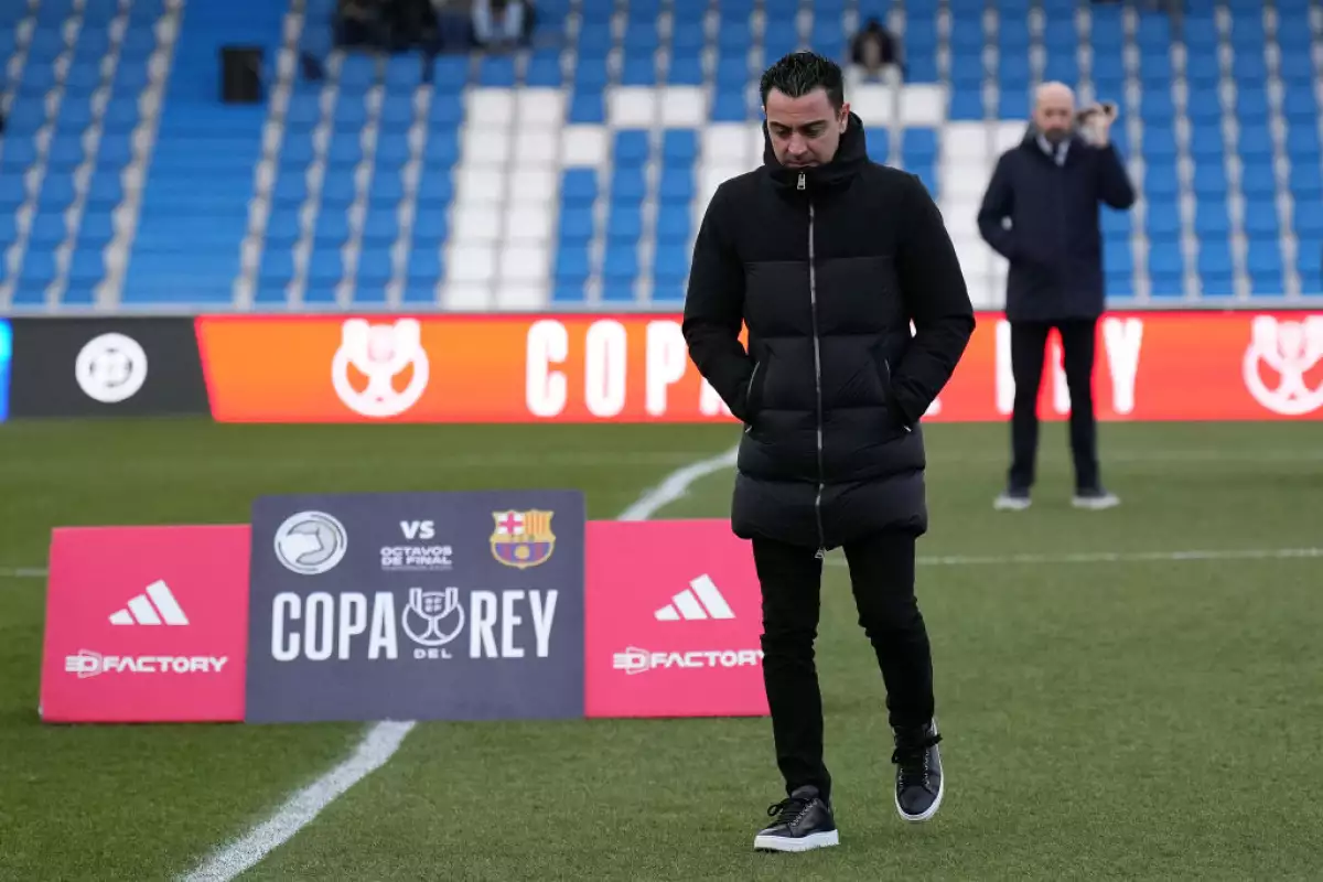 foto de xavi hernandez enel campo de juego con la cabeza gacha y chamarra