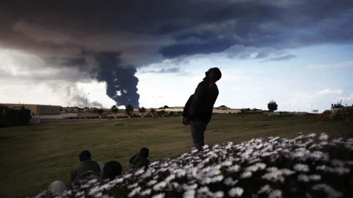 rebeldes observan una nube de humno negro en ras lanuf