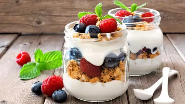 Blueberry, raspberry parfaits in mason jars, still life against wood